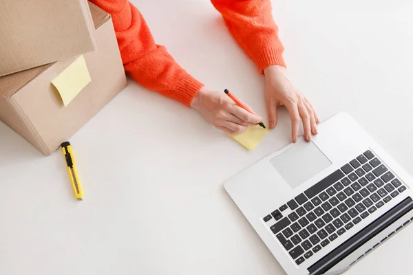 Jeune femme préparant le colis pour le client à la table — Photo