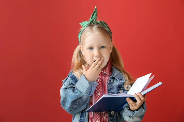 Πορτραίτο του ξαφνιασμένος μικρό κορίτσι διαβάζοντας βιβλίο για το χρώμα φόντου — Φωτογραφία Αρχείου