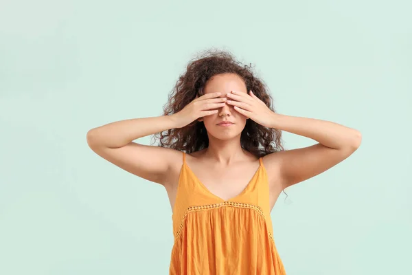 Young African-American woman covering her eyes on light background — Stock Photo, Image