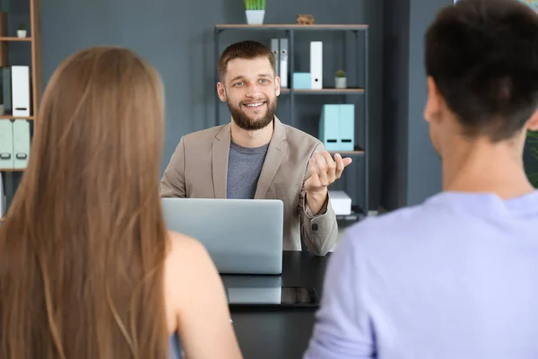 Male travel agent working with young couple in office