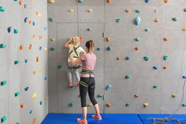 Instructor ayudando a la niña a escalar la pared en el gimnasio —  Fotos de Stock