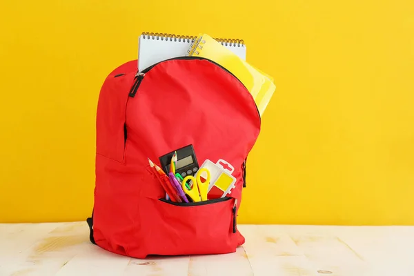 学校背包与文具在桌子上的颜色背景 — 图库照片