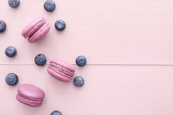 Leckere Macarons mit Blaubeeren auf farbigem Holzhintergrund — Stockfoto