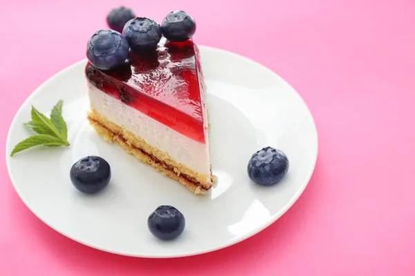 Stück leckeren Blaubeer-Käsekuchen auf farbigem Hintergrund — Stockfoto