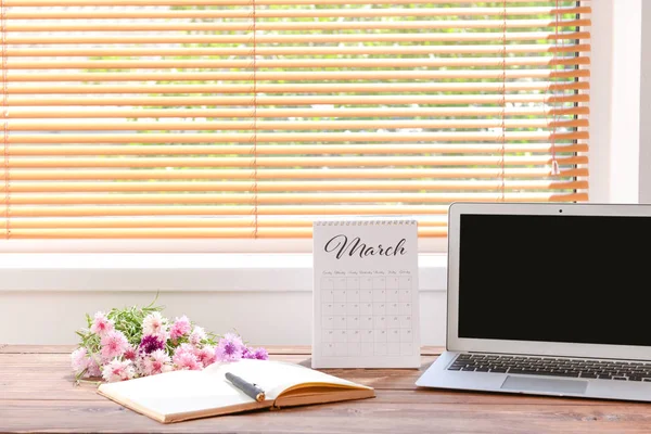 Календар з ноутбуком, квітами і канцелярськими товарами на столі біля вікна — стокове фото