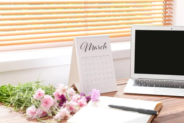 Календар з ноутбуком, квітами і канцелярськими товарами на столі біля вікна — стокове фото