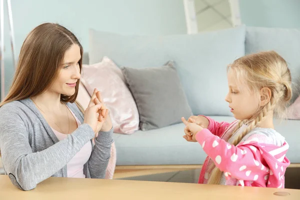 Mother teaching her deaf mute daughter to use sign language at home — Stock Photo, Image