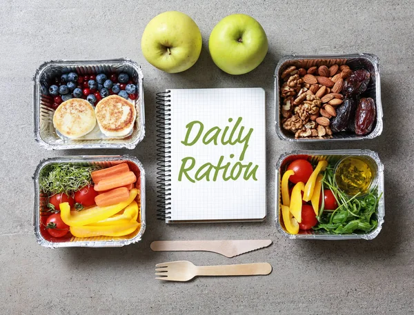 Containers with daily ration and notebook with text DAILY RATION on grey background