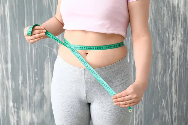 Femeia supraponderală cu bandă de măsurare pe fundal gri. Conceptul de pierdere în greutate — Fotografie, imagine de stoc