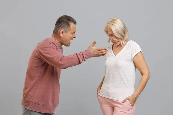 Quarrelling middle-aged couple on grey background — Stock Photo, Image