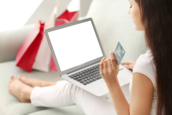Молода жінка купує онлайн з кредитною карткою і ноутбуком вдома — стокове фото