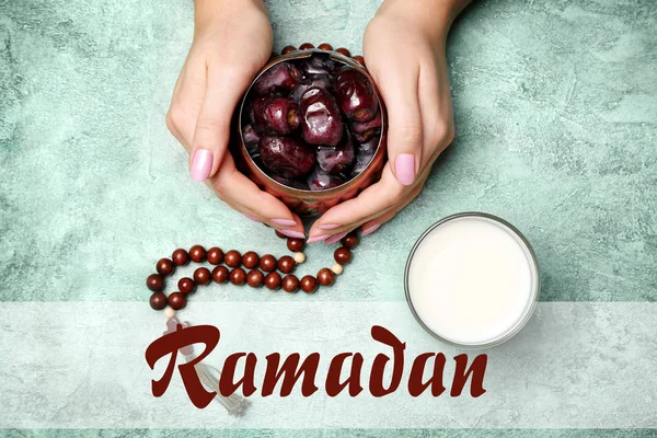 Női kéz ízletes dátumok, pohár tej és szó Ramadan színes háttér — Stock Fotó