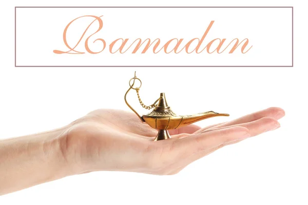 Женская рука с мусульманской лампой и слово RAMADAN на белом фоне — стоковое фото