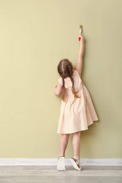 Little girl painting on color wall in room — Stock Photo, Image