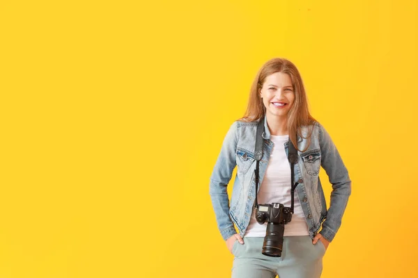 Young female photographer on color background — Stock Photo, Image