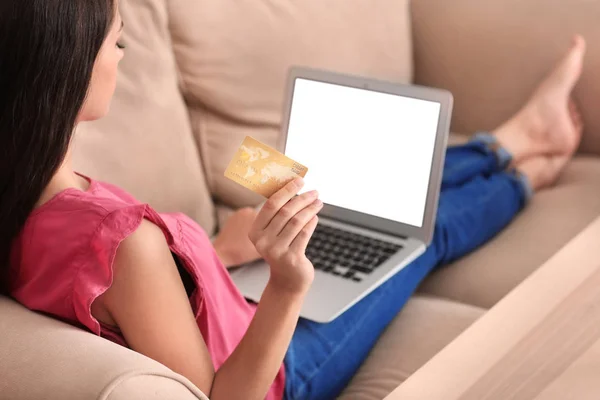 Jeune femme faisant du shopping en ligne avec carte de crédit et ordinateur portable à la maison — Photo