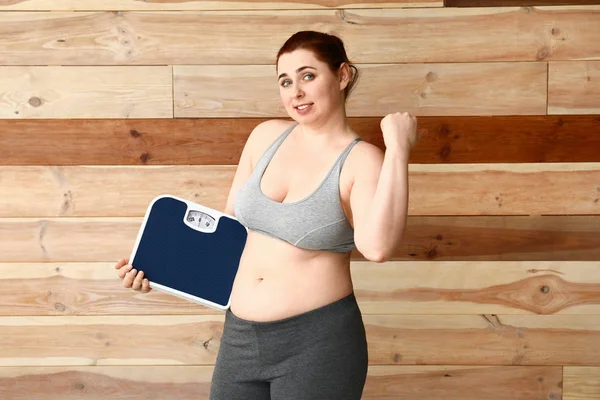 Mujer con sobrepeso y escamas sobre fondo de madera. Concepto de pérdida de peso — Foto de Stock
