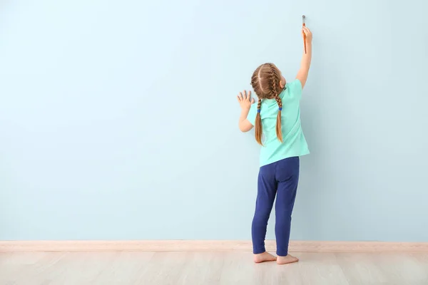 Маленькая девочка рисует на светлой стене в комнате — стоковое фото