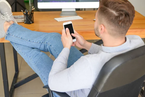 Handsome man with mobile phone resting in office — Stock Photo, Image