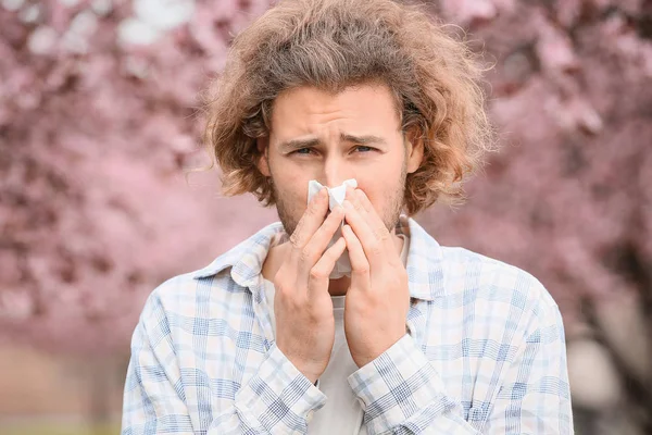 Sick man with nose wiper on spring day — Stock Photo, Image