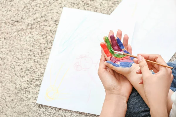 Mutter bemalt Hände ihres kleinen Sohnes zu Hause — Stockfoto