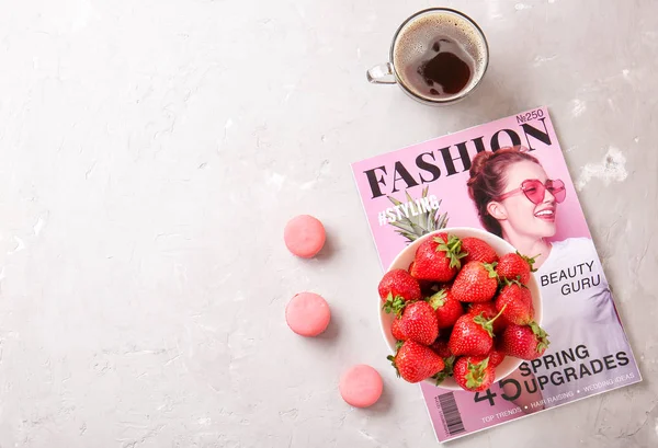 Skål med mogen jordgubb, modemagasin, kopp kaffe och makaroner på ljus bakgrund — Stockfoto