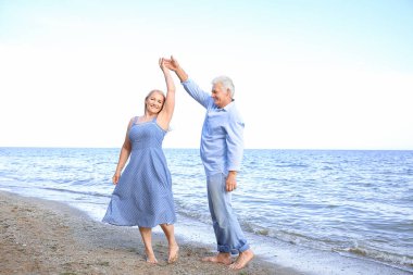 Happy mature couple dancing at sea resort clipart