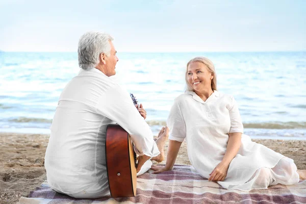 Olgun adam oyun gitar için onun eş at deniz Resort — Stok fotoğraf