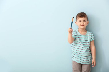 Renk arka plan üzerinde fırça ile sevimli küçük çocuk