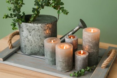 Yanan mumlar ve Sulama can renk arka plana karşı masada okaliptüs dalları ile