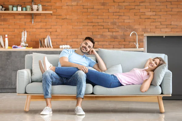 Feliz pareja joven descansando juntos en el sofá en casa —  Fotos de Stock