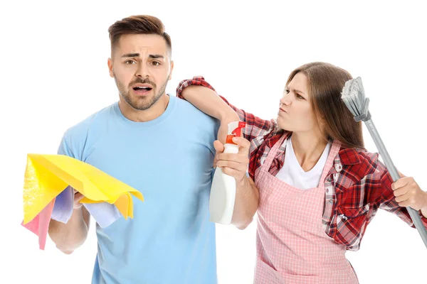 Angry wife and her afraid husband with cleaning supplies on white background — Stock Photo, Image