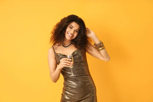 Portrait de femme afro-américaine heureuse avec verre de champagne sur fond de couleur — Photo