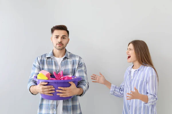 Dühös feleség szidás ő szomorú férje tisztító ellátás szürke háttér — Stock Fotó