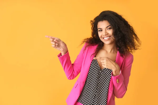 Portrait of stylish African-American woman pointing at something on color background — Stock Photo, Image