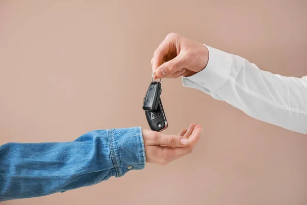 Продавець дає ключі від автомобіля жінці на кольоровому фоні — стокове фото