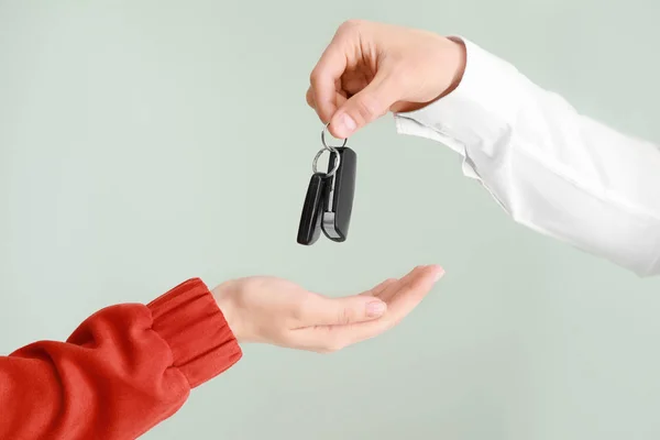 Salesman giving car keys to woman on light background — Stock Photo, Image