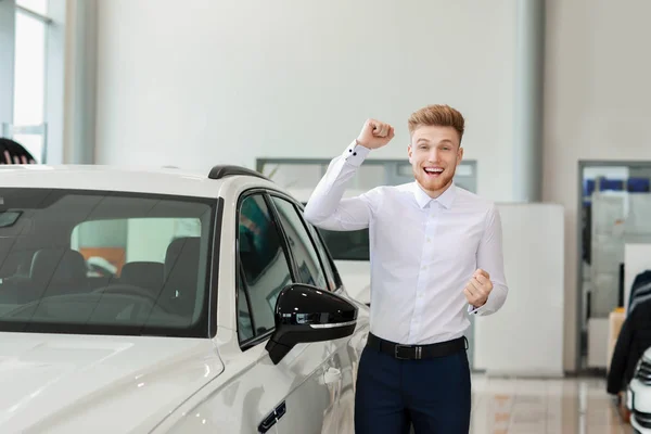 Happy man buying new car in salon — Stock Photo, Image
