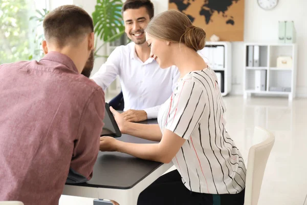 Agente de viajes masculino trabajando con parejas jóvenes en la oficina — Foto de Stock