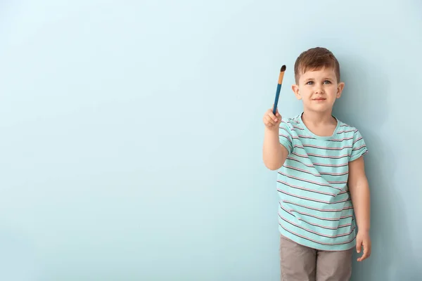 Lindo niño con cepillo en el fondo de color — Foto de Stock