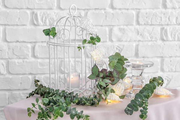 Decorative cage, burning candles and eucalyptus branches on table — Stock Photo, Image