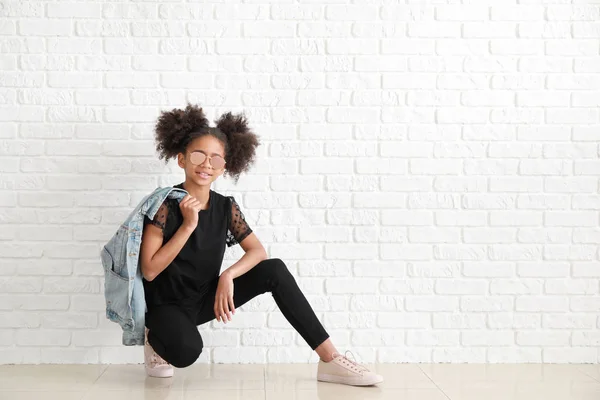 Elegante ragazza afro-americana in jeans vicino al muro di mattoni bianchi — Foto Stock
