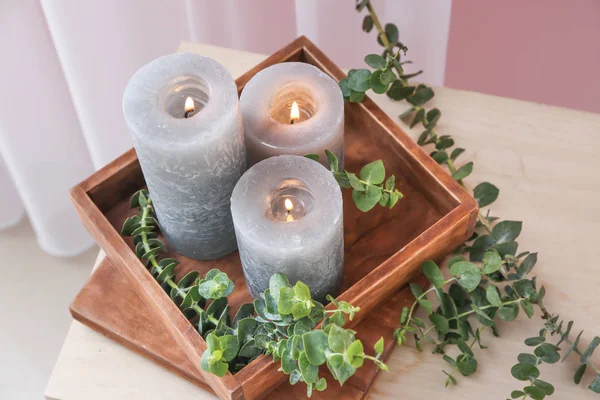 Box with burning candles and eucalyptus branches on table — Stock Photo, Image