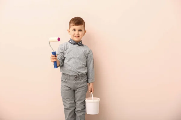 Cute little boy with paint roller and bucket on color background — Stock Photo, Image