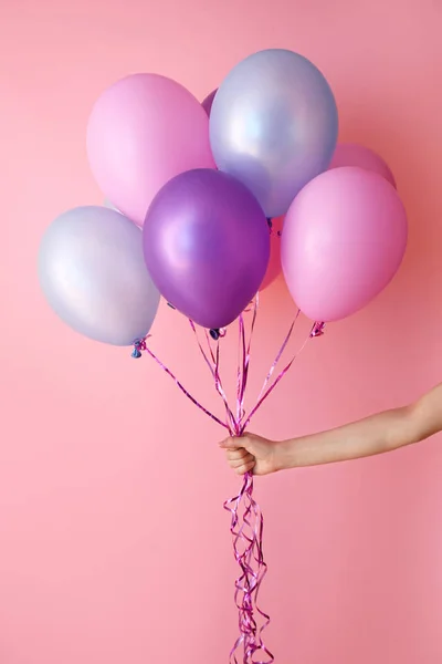 Vrouwelijke hand met lucht ballonnen op kleur achtergrond — Stockfoto