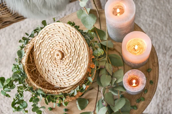 Scatola di vimini, candele accese e rami di eucalipto sul tavolo in camera — Foto Stock