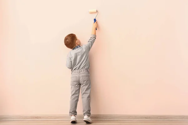 Симпатичный маленький мальчик рисует стену в комнате — стоковое фото