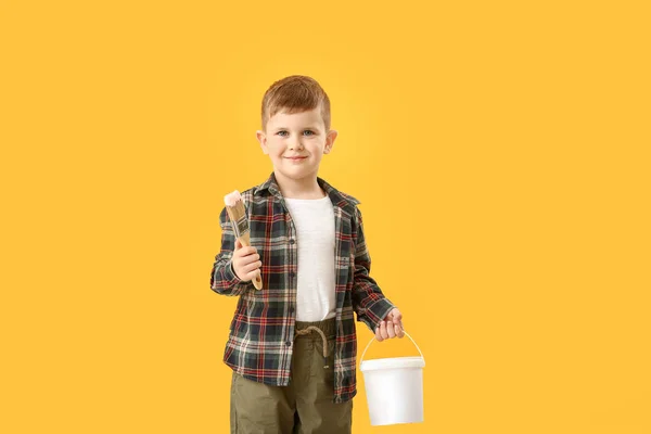 Cute little boy with brush and bucket of paint on color background — Stock Photo, Image