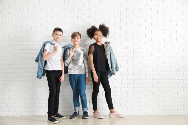 Niños con estilo en ropa vaquera cerca de la pared de ladrillo blanco — Foto de Stock