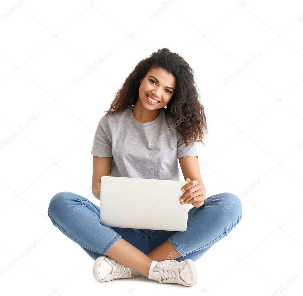 Portrait of happy African-American woman with laptop on light background